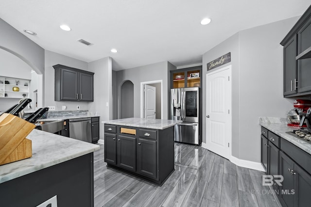 kitchen with appliances with stainless steel finishes, light stone countertops, and a kitchen island