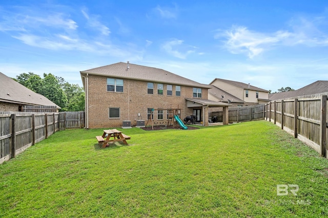 rear view of property featuring a yard, a playground, and central air condition unit