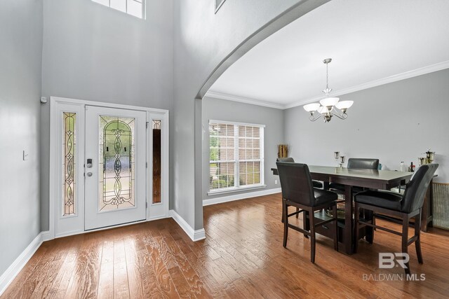 foyer featuring crown molding, hardwood / wood-style floors, a high ceiling, and a notable chandelier