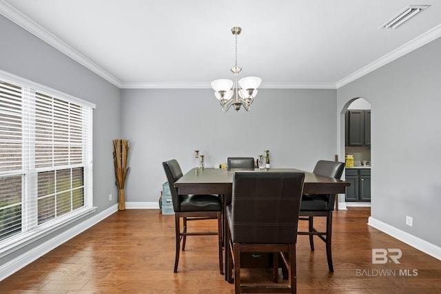 dining area with dark hardwood / wood-style flooring, ornamental molding, and a chandelier