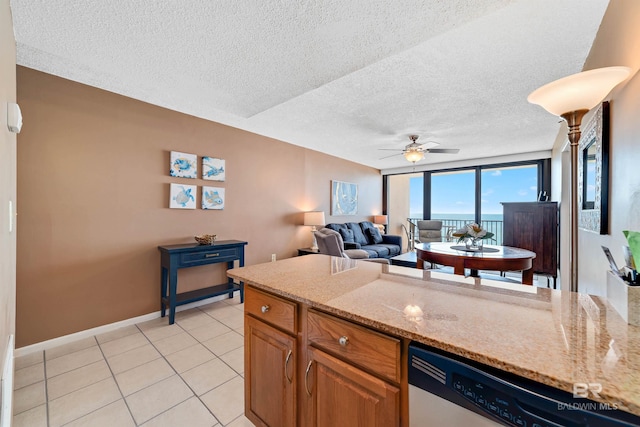 kitchen with light stone countertops, a textured ceiling, stainless steel dishwasher, and ceiling fan