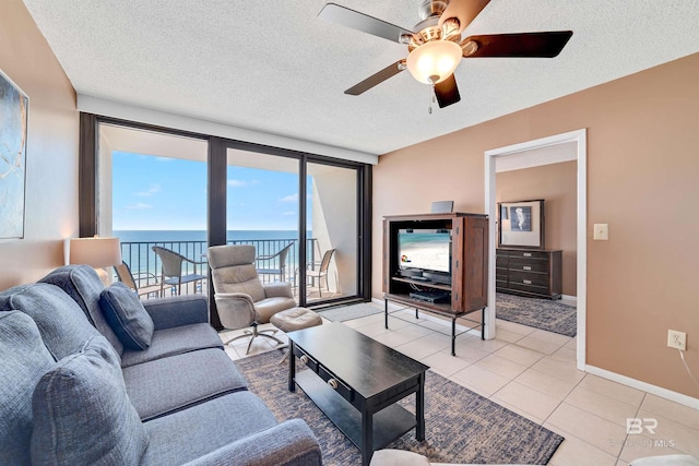 living room with ceiling fan, light tile patterned floors, and a textured ceiling