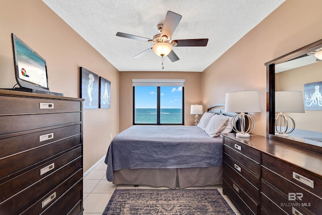 bedroom with ceiling fan, a water view, light tile patterned floors, and a textured ceiling