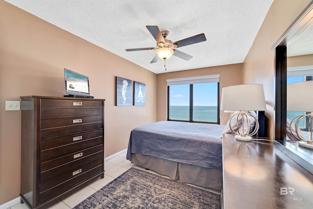 bedroom with ceiling fan, light tile patterned floors, and a textured ceiling