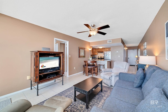 living room with ceiling fan, light tile patterned floors, and a textured ceiling