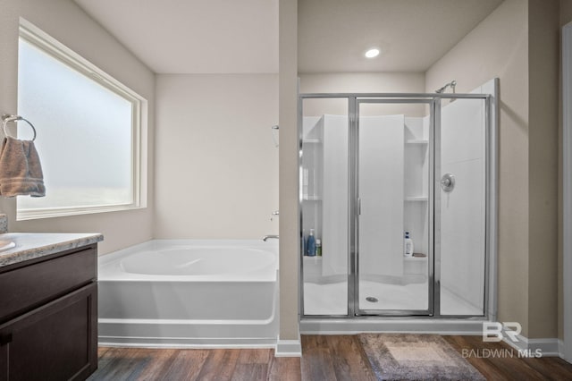 bathroom with hardwood / wood-style floors, vanity, and plus walk in shower