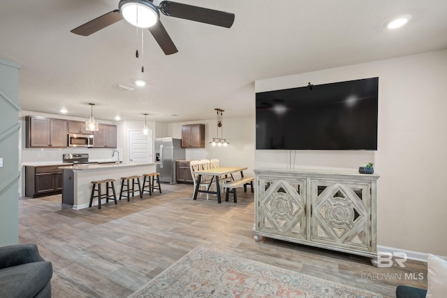 living room with ceiling fan, light hardwood / wood-style floors, and sink