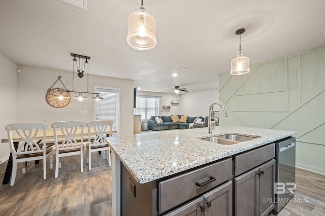 kitchen featuring sink, stainless steel dishwasher, dark hardwood / wood-style floors, pendant lighting, and a kitchen island with sink