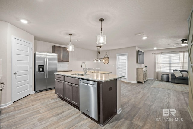 kitchen with pendant lighting, a center island with sink, sink, light hardwood / wood-style floors, and stainless steel appliances