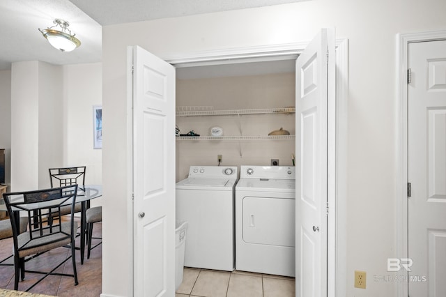 clothes washing area with washing machine and dryer, laundry area, and light tile patterned flooring