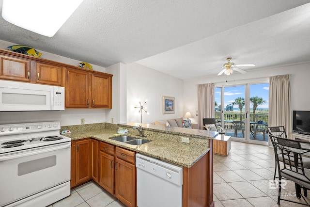 kitchen with a peninsula, white appliances, a sink, open floor plan, and brown cabinets