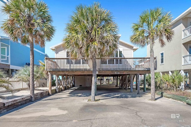 raised beach house featuring a deck, a carport, and driveway