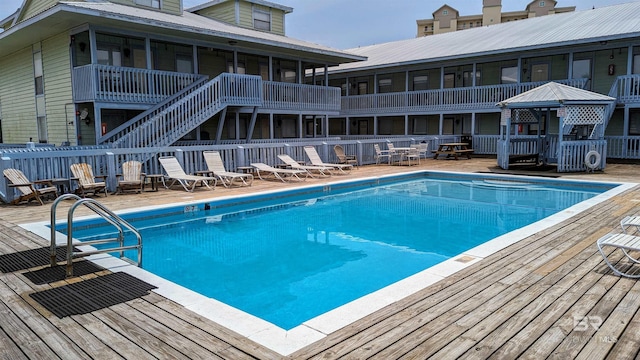 view of pool featuring a sunroom and a wooden deck