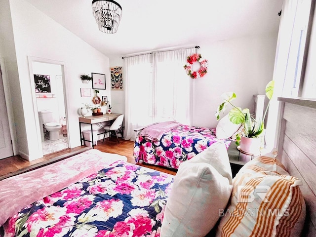 bedroom featuring ensuite bath, hardwood / wood-style floors, and vaulted ceiling