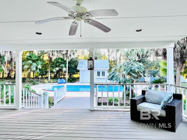 view of swimming pool featuring ceiling fan and a wooden deck