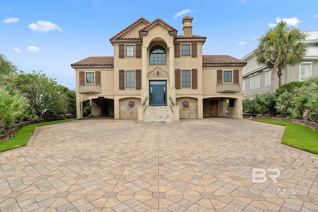 28452 Ono Blvd, Orange Beach, AL 36561 - view of front of house featuring a carport, decorative driveway, stucco siding, a tiled roof, and a chimney
