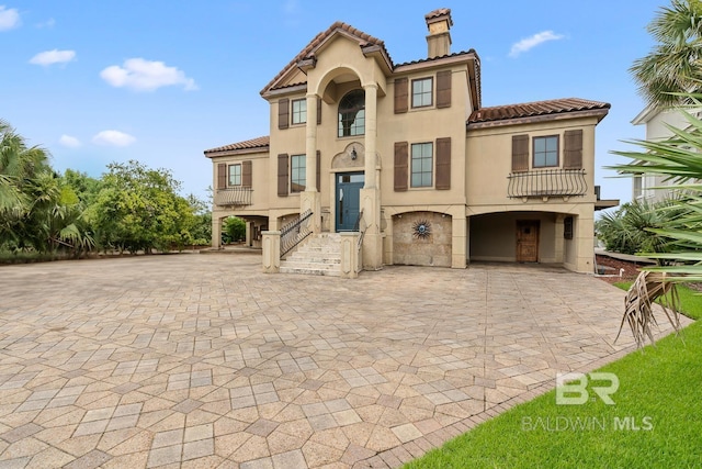 28452 Ono Blvd, Orange Beach, AL 36561 - view of front facade featuring a tile roof, stucco siding, a chimney, and decorative driveway