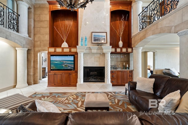 28452 Ono Blvd, Orange Beach, AL 36561 - living area featuring decorative columns, arched walkways, light tile patterned flooring, a tile fireplace, and a high ceiling