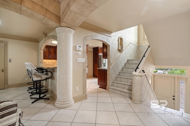 28452 Ono Blvd, Orange Beach, AL 36561 - foyer entrance featuring light tile patterned flooring, crown molding, stairway, ornate columns, and arched walkways