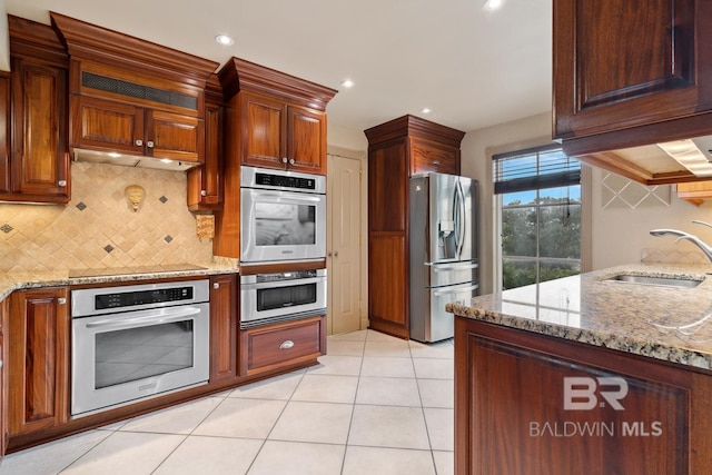 28452 Ono Blvd, Orange Beach, AL 36561 - kitchen featuring appliances with stainless steel finishes, tasteful backsplash, light stone countertops, light tile patterned flooring, and recessed lighting