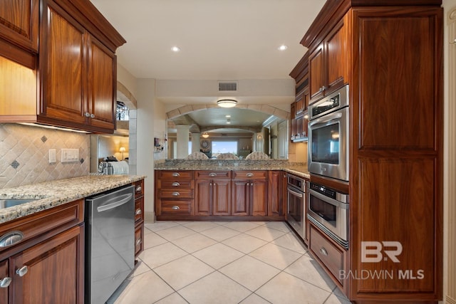 28452 Ono Blvd, Orange Beach, AL 36561 - kitchen with stainless steel appliances, decorative backsplash, light stone counters, light tile patterned floors, and a peninsula