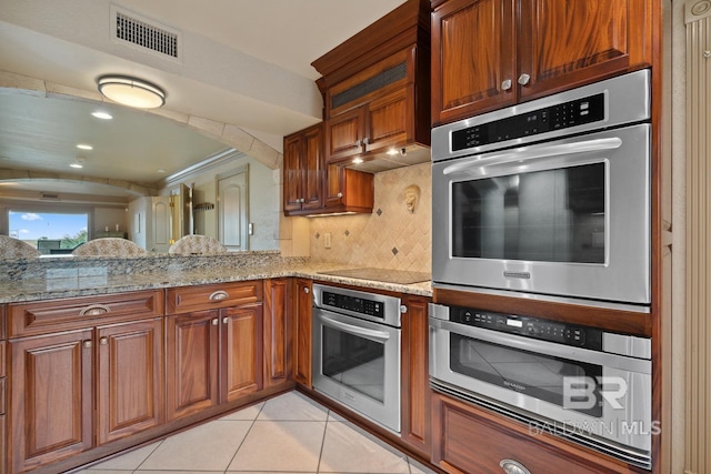 28452 Ono Blvd, Orange Beach, AL 36561 - kitchen featuring stainless steel oven, light tile patterned floors, light stone countertops, and brown cabinets