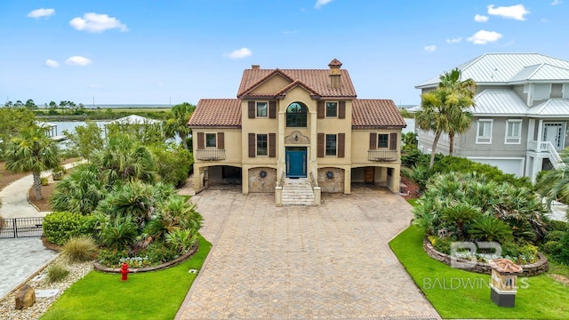 28452 Ono Blvd, Orange Beach, AL 36561 - mediterranean / spanish house featuring a chimney, a tiled roof, a carport, stucco siding, and driveway