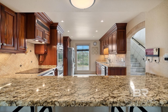 28452 Ono Blvd, Orange Beach, AL 36561 - kitchen featuring appliances with stainless steel finishes, light stone countertops, backsplash, a peninsula, and recessed lighting