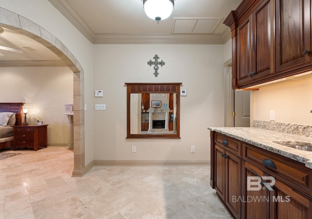 28452 Ono Blvd, Orange Beach, AL 36561 - kitchen with arched walkways, light stone countertops, crown molding, and a ceiling fan