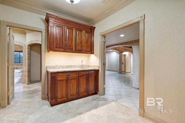 28452 Ono Blvd, Orange Beach, AL 36561 - kitchen with arched walkways, light stone counters, decorative columns, and crown molding