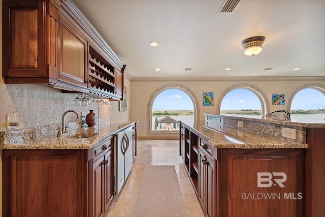 28452 Ono Blvd, Orange Beach, AL 36561 - kitchen featuring decorative backsplash, light stone countertops, recessed lighting, ornamental molding, and a water view