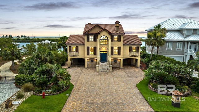 28452 Ono Blvd, Orange Beach, AL 36561 - mediterranean / spanish-style house featuring a tile roof, a chimney, decorative driveway, a carport, and stucco siding