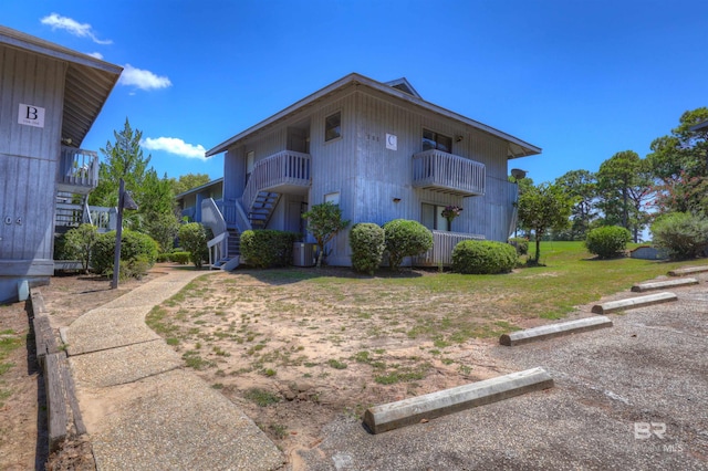 exterior space with a balcony, a lawn, and cooling unit