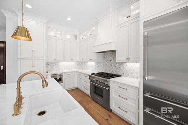 kitchen with premium range hood, sink, pendant lighting, high quality appliances, and white cabinets