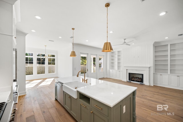 kitchen with sink, built in shelves, ceiling fan, a fireplace, and decorative light fixtures