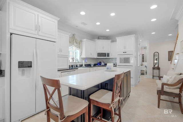 kitchen featuring white cabinets, white appliances, recessed lighting, a breakfast bar area, and a center island