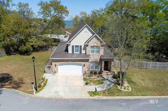 craftsman-style home featuring stone siding, concrete driveway, fence, board and batten siding, and metal roof