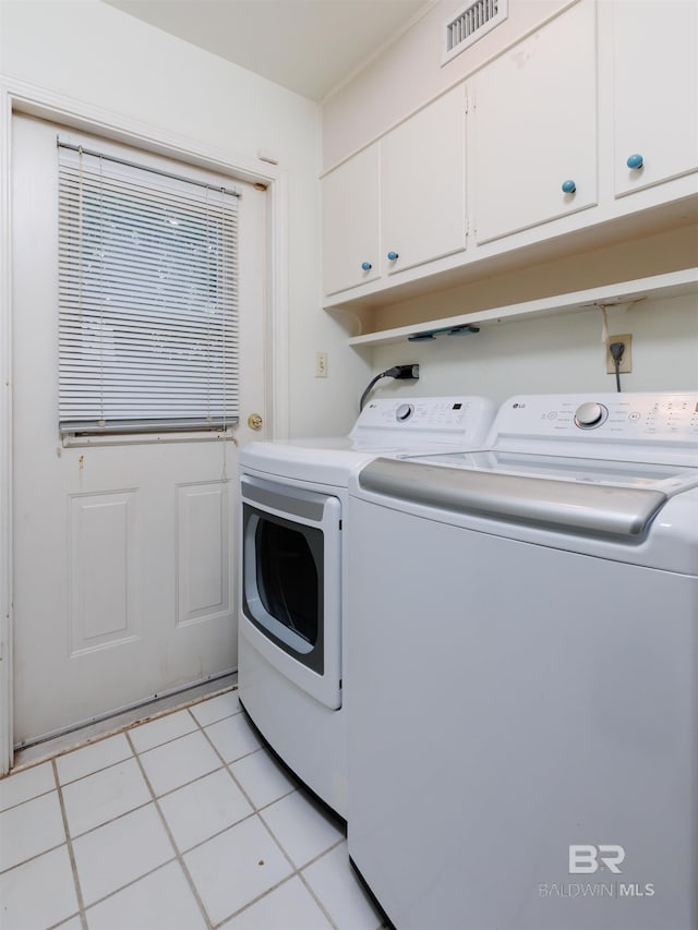 washroom with cabinets, washing machine and dryer, and light tile patterned flooring