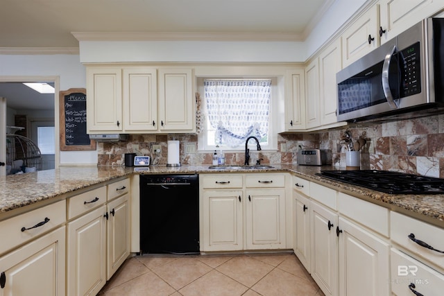 kitchen with decorative backsplash, light stone countertops, sink, and black appliances