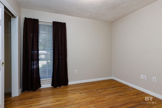 unfurnished room featuring a textured ceiling and wood-type flooring