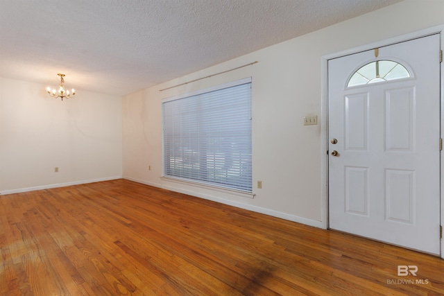 entrance foyer featuring a textured ceiling, hardwood / wood-style floors, and a chandelier