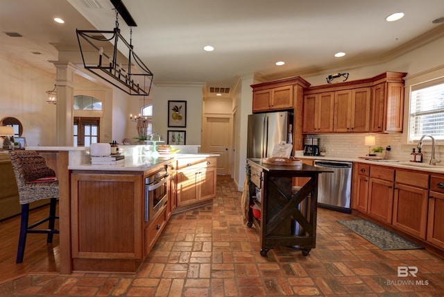 kitchen with a spacious island, appliances with stainless steel finishes, brown cabinetry, and crown molding