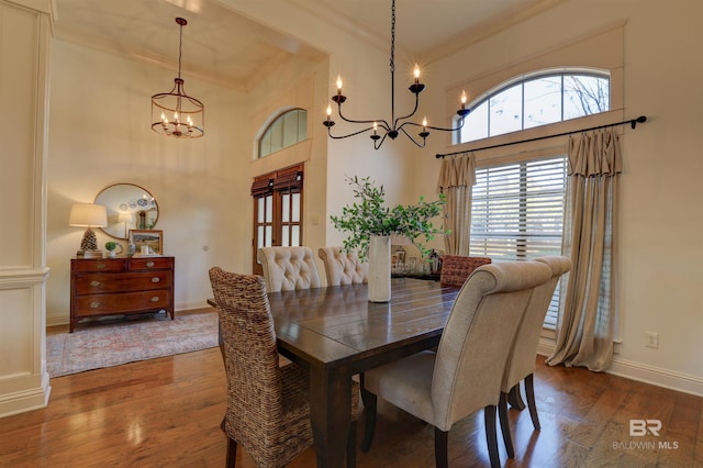 dining area with a high ceiling, wood finished floors, baseboards, and a chandelier