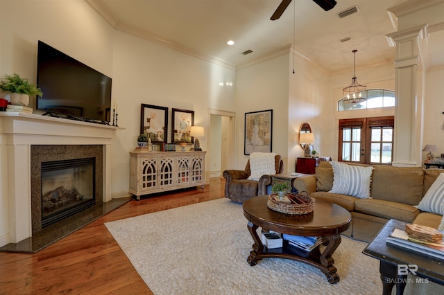 living room with a high end fireplace, visible vents, ornamental molding, french doors, and wood finished floors