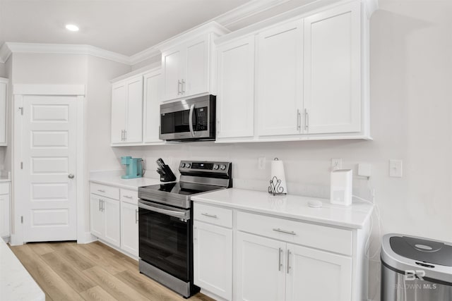 kitchen featuring stainless steel appliances, light countertops, light wood-style floors, ornamental molding, and white cabinetry