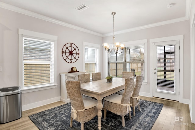 dining space with light wood finished floors, plenty of natural light, an inviting chandelier, and crown molding