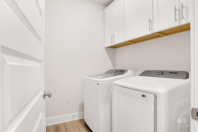 clothes washing area with baseboards, independent washer and dryer, cabinet space, and light wood-style floors