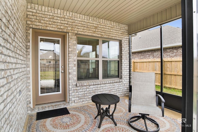 entrance to property featuring fence, a patio, and brick siding