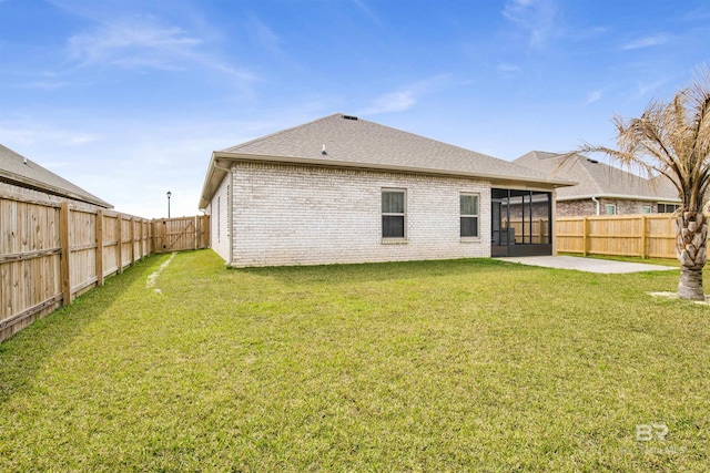 back of property with a fenced backyard, a lawn, and brick siding