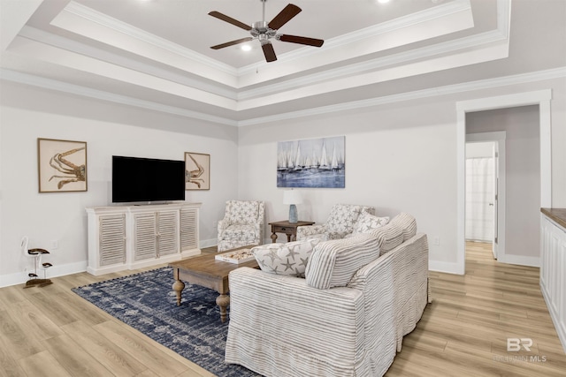 living area featuring ornamental molding, a raised ceiling, baseboards, and light wood finished floors